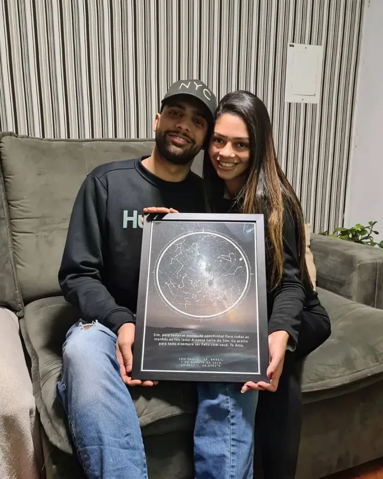 Casal sentado no sofá segurando o quadro Classic